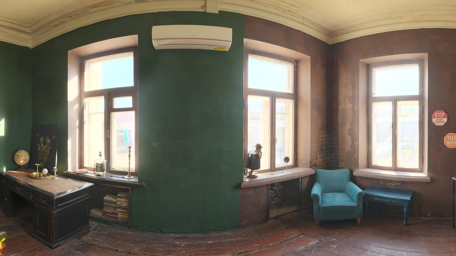 Vue d’ensemble panoramique d’un intérieur : murs vert profond, hautes fenêtres, parquet ancien et moulures