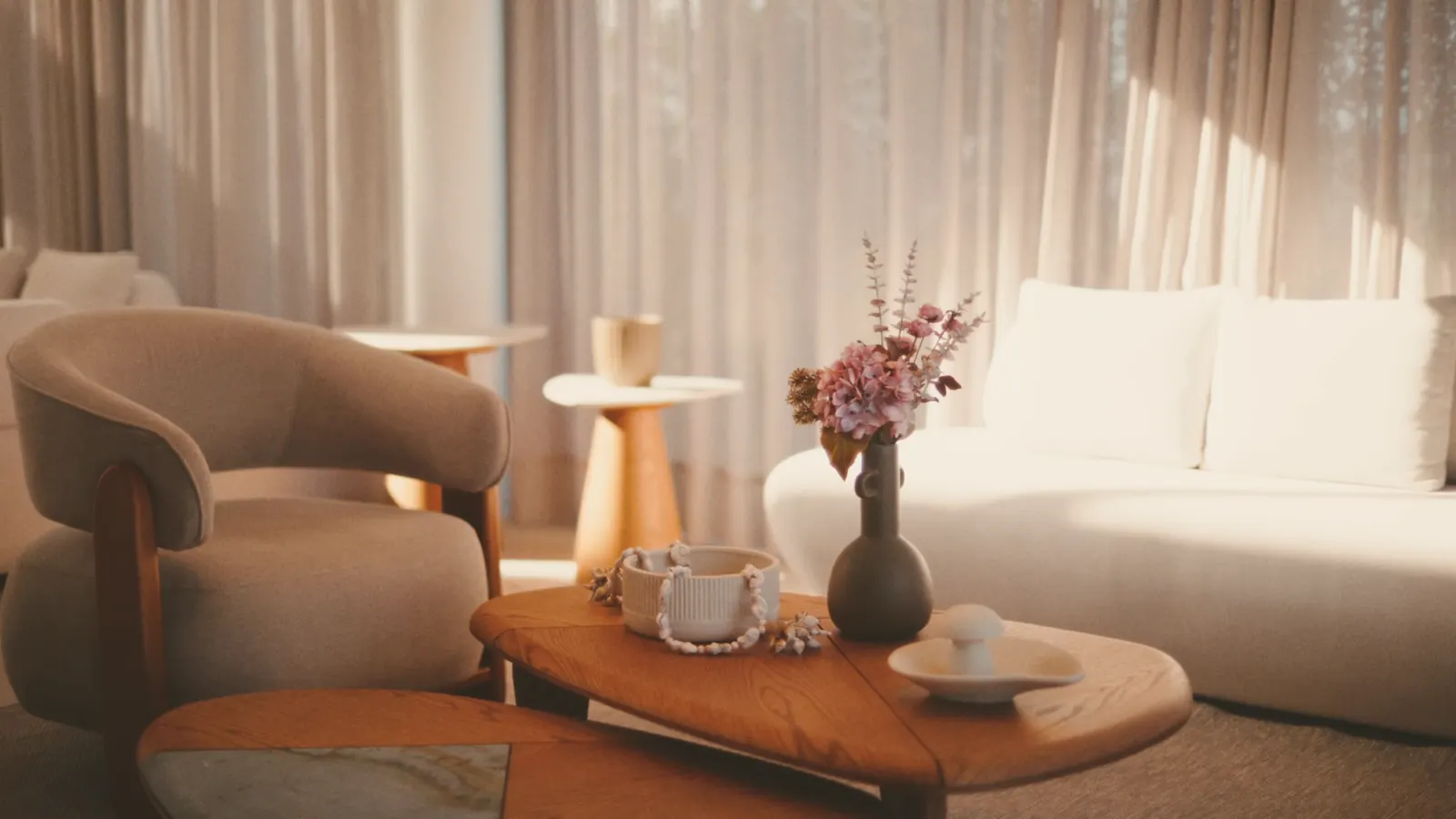 Le lieu aménagé : fauteuil enveloppant en bouclette, table basse en bois massif, canapé blanc arrondi, voilages en lin