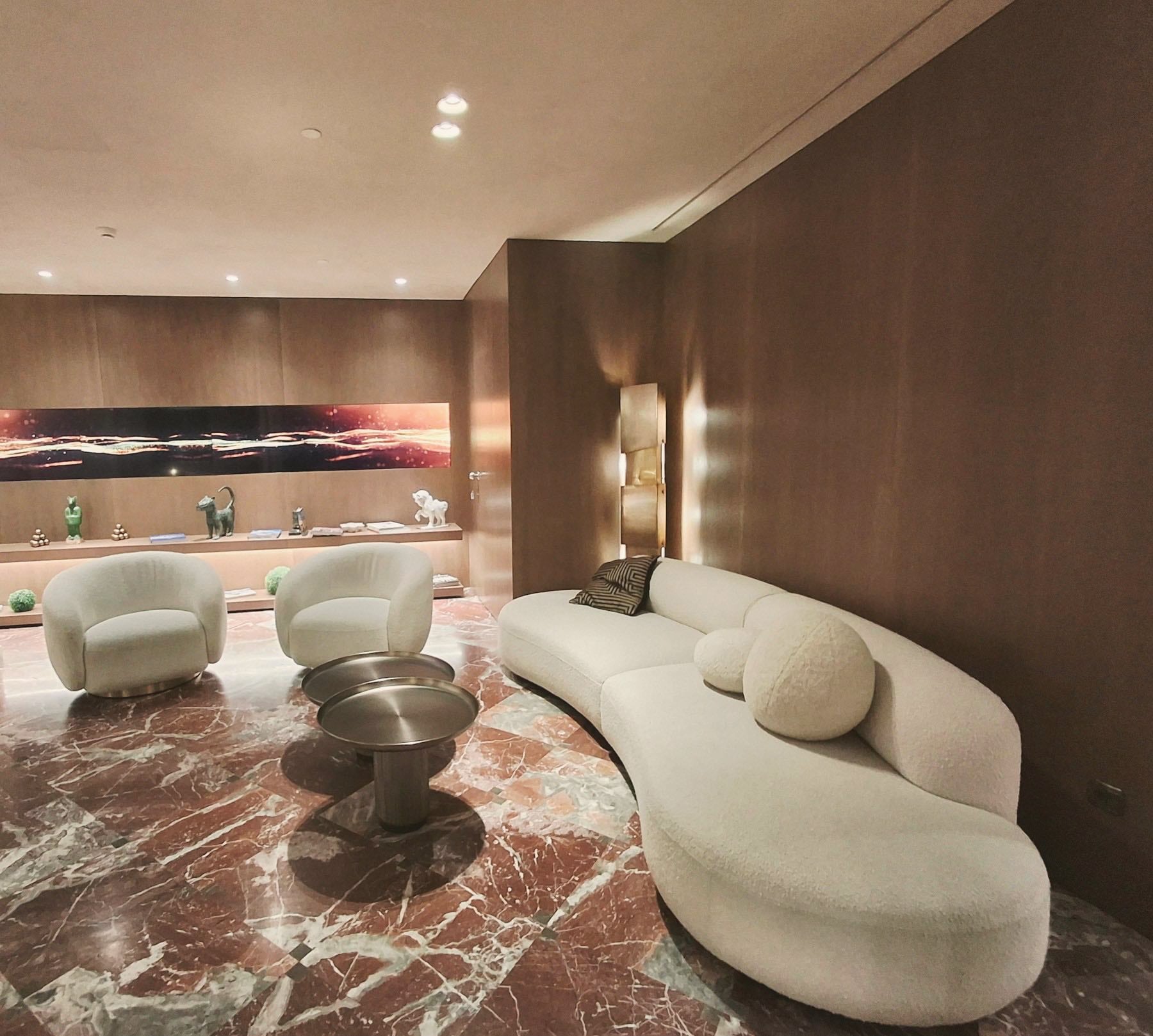 Banquette courbe en bouclette crème dans un lobby aux murs en bois sombre