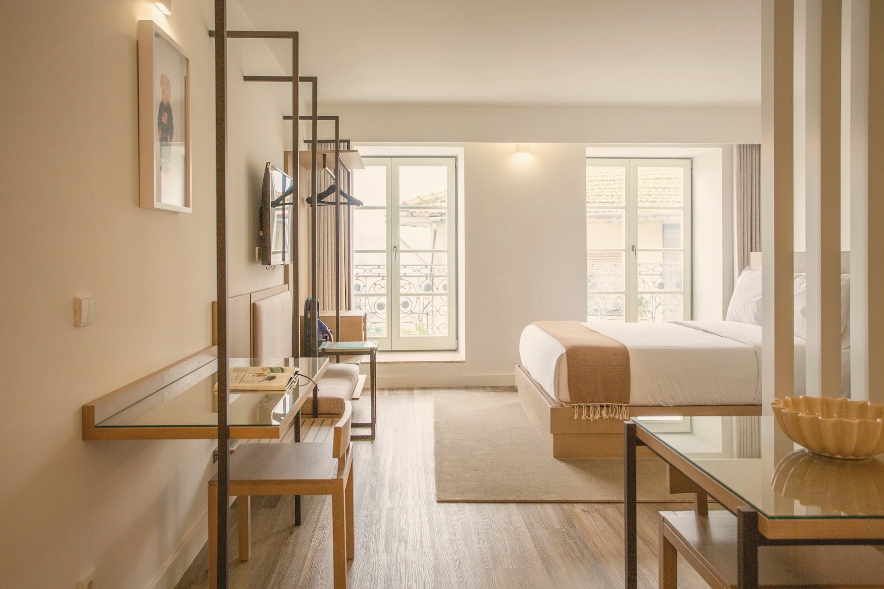 Chambre d’hôtel lumineuse : parquet, bureau en verre et bois, linge blanc