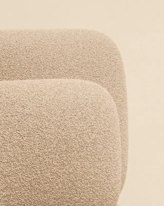 Gros plan d’un tissu bouclette écru sur les courbes d’un fauteuil