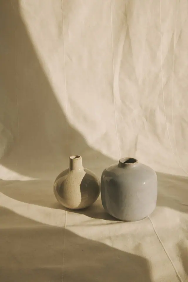 Deux petits vases en céramique mate sur un drapé de lin, lumière naturelle